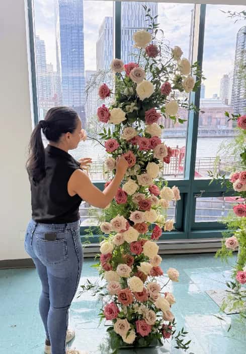 A Stemmery florist placing roses into a tall floral column