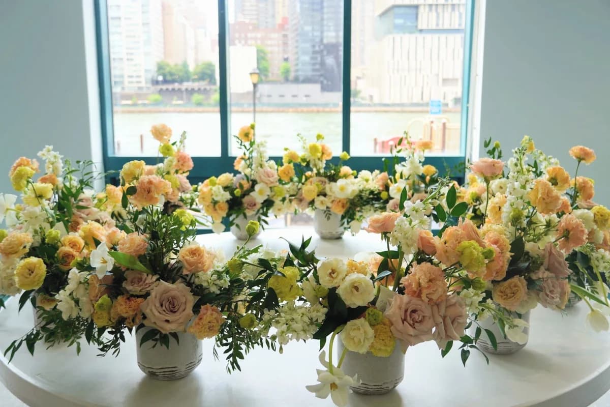 Peach, yellow and white centerpieces on a round table by a riverside window